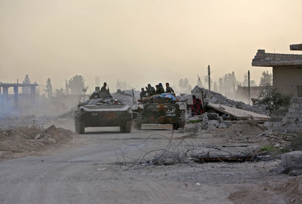 Syrian government forces drive military vehicles in Al-Shifoniya as they advance in the rebel-held Eastern Ghouta area. — AFP