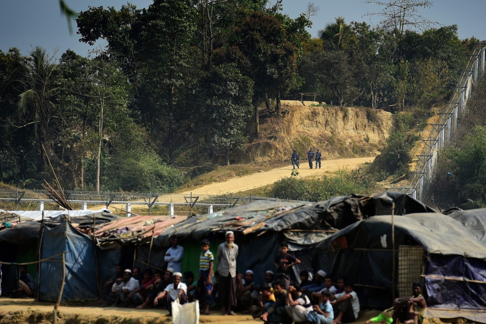 A Myanmar security personnel keeps watch along the Myanmar-Bangladesh border as Rohingya refugee sit outside their makeshifts shelters near Tombru, in the Bangladeshi district of Bandarban, in this March 1, 2018 file photo. — AFP