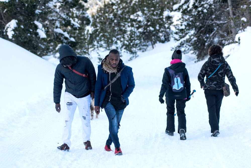 In this file photo taken on Jan. 13, 2018, two migrants from Ivory Coast walk past hikers on their way to the Colle della Scala (Col de l'Echelle) a snow-covered pass, to cross the border between Italy and France near Bardonecchia, Italian Alps. - AFP