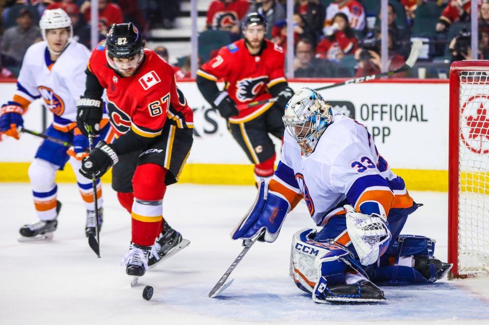 New York Islanders’ goaltender Christopher Gibson (R) makes a save against Calgary Flames’ right wing Michael Frolik (2nd L) during their NHL game at Scotiabank Saddledome in Calgary Sunday. — Reuters
