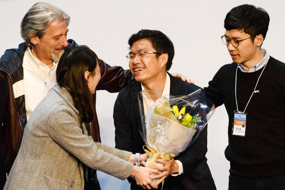 Pro-democracy candidate Au Nok-hin, second right, is congratulated by disqualified lawmaker Nathan Law, right, disqualified candidate Agnes Chow, second left, and defeated pro-democracy candidate Paul Zimmerman, left, after Au won the Legislative Council by-election for the Hong Kong Island constituency in Hong Kong on Monday. — AFP