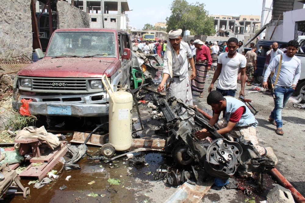 A picture taken on Tuesday in the southern Yemeni city and government bastion of Aden shows a Yemeni inspecting debris and car wreckage in the aftermath of an explosion from a suicide bombing claimed by the Daesh group which hit UAE-trained Yemeni troops. — AFP