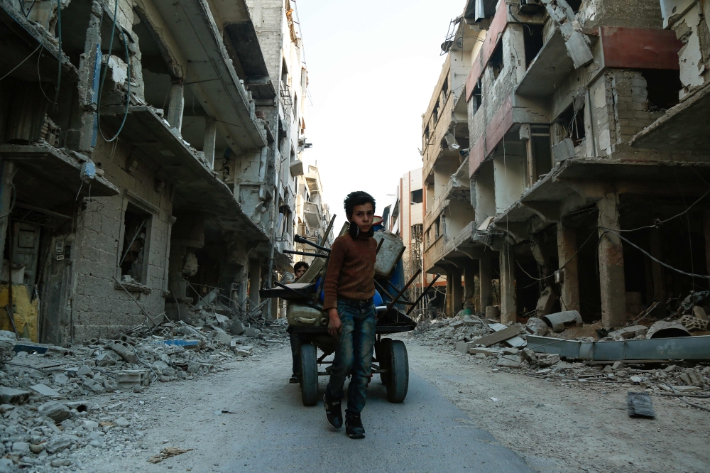 Internally displaced people ride on the back of a truck with their belongings in the town of Inab, eastern Afrin. — Reuters