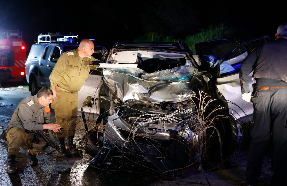 Israeli security forces and forensics inspect the destroyed vehicle that was used by an assailant in a car ramming attack targeting a group of Israeli soldiers near Mevo Dotan in the north of the occupied West Bank. — AFP