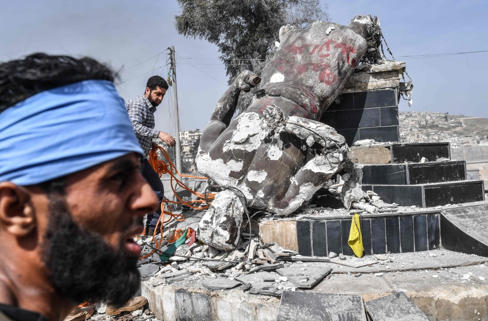 Turkish-backed Syrian rebels remove a rope from the statue of 