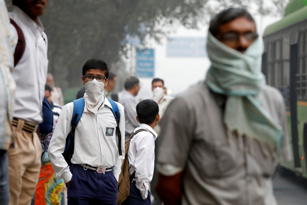 A schoolboy covers his face with a handkerchief as he waits for a passenger bus on a smoggy morning in New Delhi, India, in this Nov. 8, 2017 file photo. — Reuters