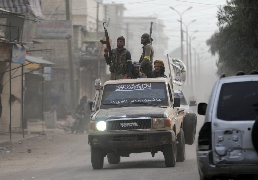 Turkish-backed Free Syrian Army fighters hold their weapons as they stand on the back of a truck in Afrin. — Reuters