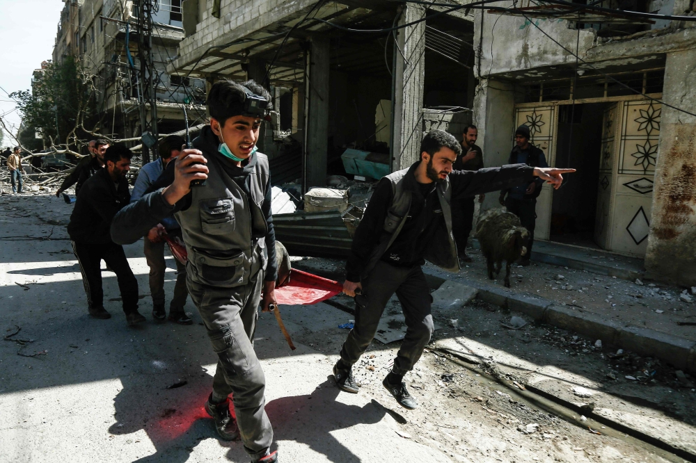 Members of the Syrian Civil Defense (known as the White Helmets) carry a wounded man on a stretcher following air strikes on Douma, the main town of Syria's rebel enclave of Eastern Ghouta. — AFP