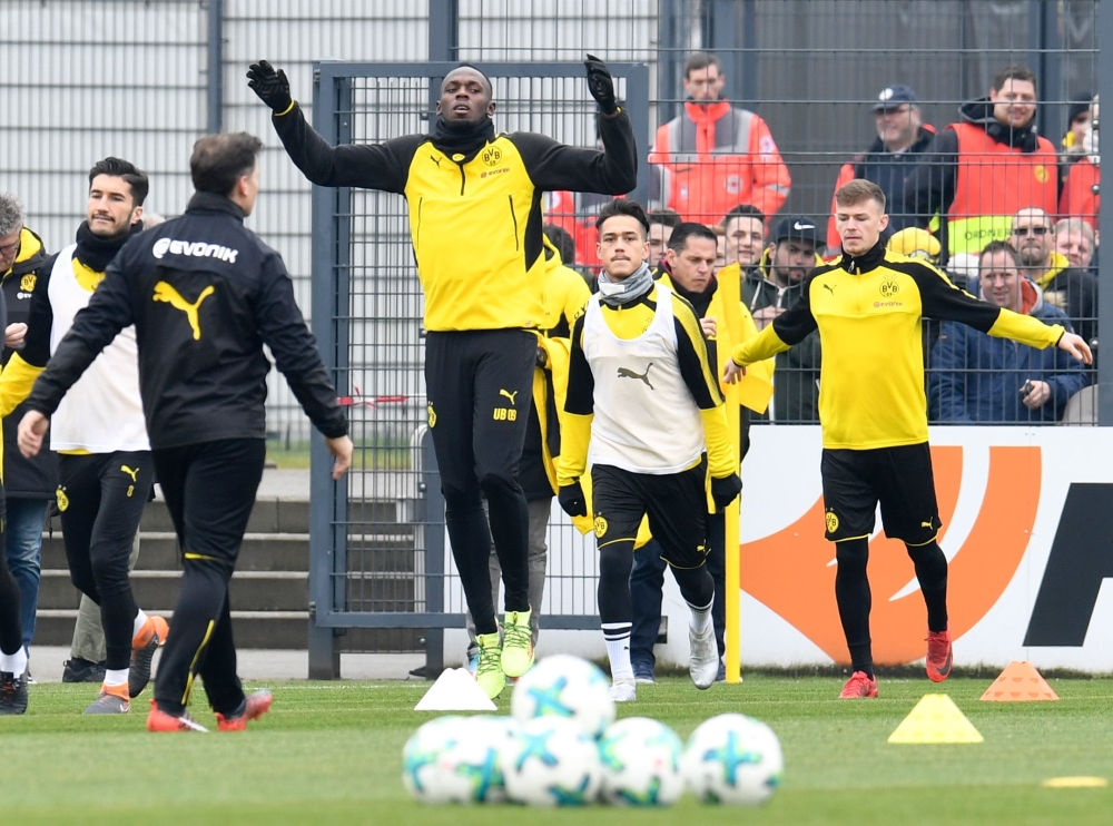 Retired Jamaican Olympic and World champion sprinter Usain Bolt (2ndL) warms up as he takes part in a training session of German first Bundesliga football team Dortmund, on Friday, in Dortmund. Behind him is written 