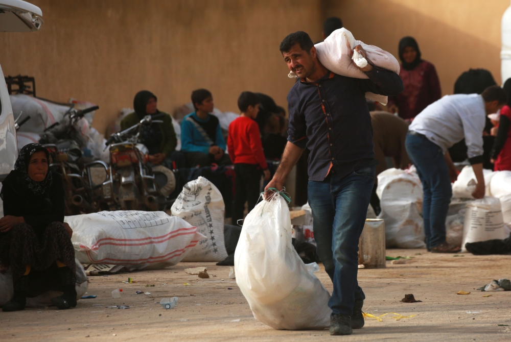 A boy carries bags at a make-shift camp where displaced Syrians from Tal Rafaat and areas around Afrin are taking shelter near the village of Kharufiyah on the southern outskirts of Manbij, on Thursday. — AFP