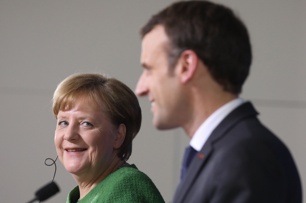 Germany’s Chancellor Angela Merkel, left, looks at French president Emmanuel Macron during a joint press conference with on the second day of a summit of European Union (EU) leaders in Brussels on Friday. — AFP