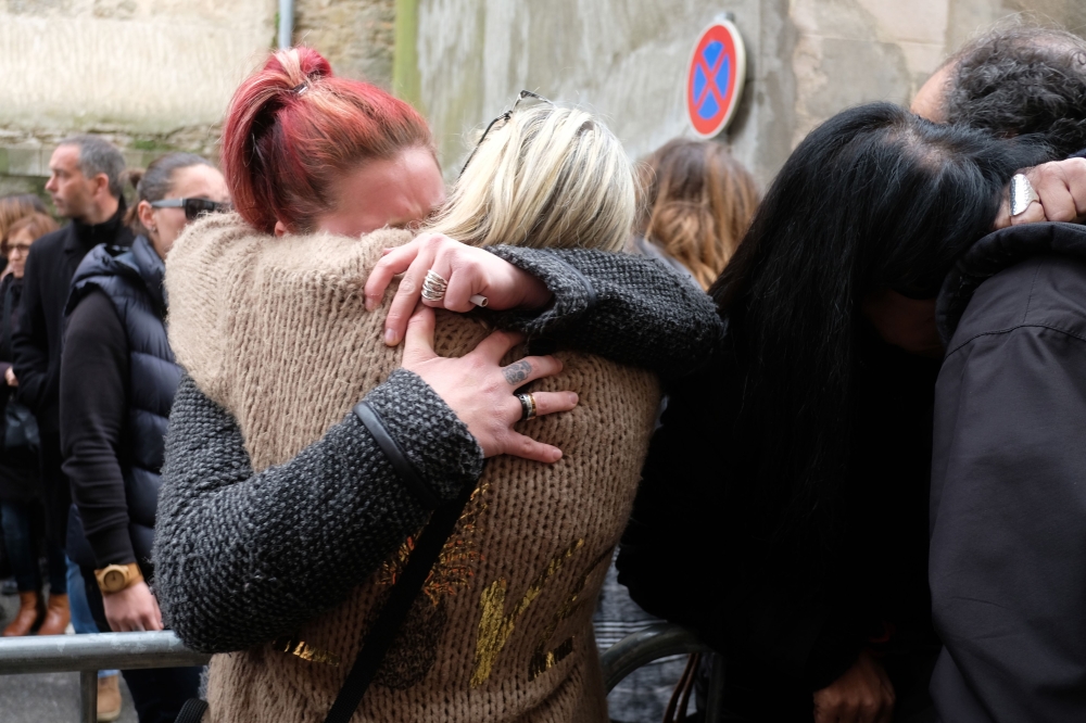 People console each other outside the Saint Etienne Church in Trebes in southwest France, after a service of remembrance to victims on Sunday, two days after a man carried out an attack in which four people were killed. — AFP  