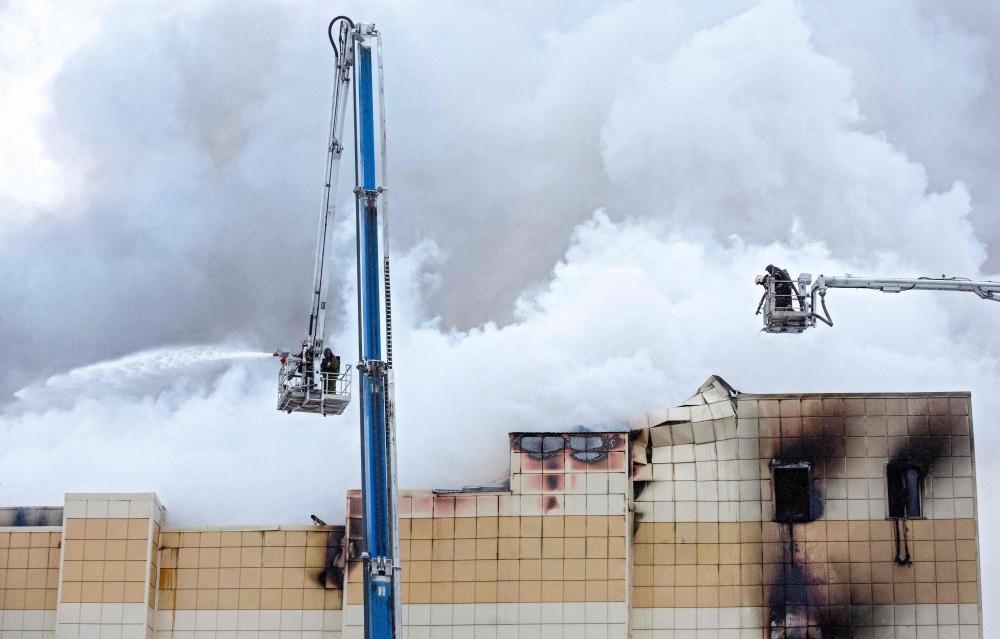 A picture taken on March 25, 2018, shows emergency firefighters extinguishing a fire outside a burning shopping centre in Kemerovo. — AFP