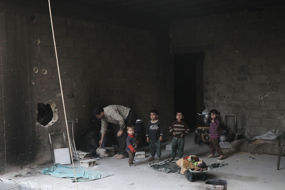 Syrian children stand in a basement used as a shelter against air strikes in Douma, in Eastern Ghouta on the outskirts of the capital Damascus. — AFP