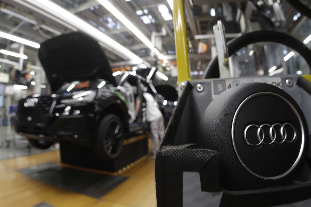 Employees of German car producer Audi work on the assembly line production site in Ingolstadt, Germany. Automakers are gradually adding advanced electronic safety features to human-driven cars as they step toward a world of self-driving vehicles. - AP