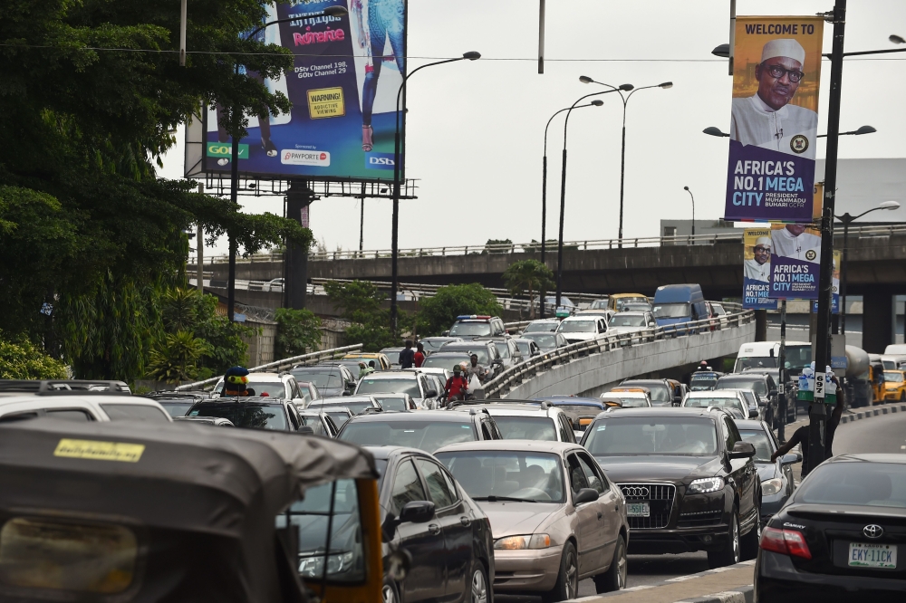 Motorists wait in a traffic jam under banners bearing a portrait of Nigerian President Muhammadu Buhari, who is on official visit to Lagos, on Thursday. — AFP