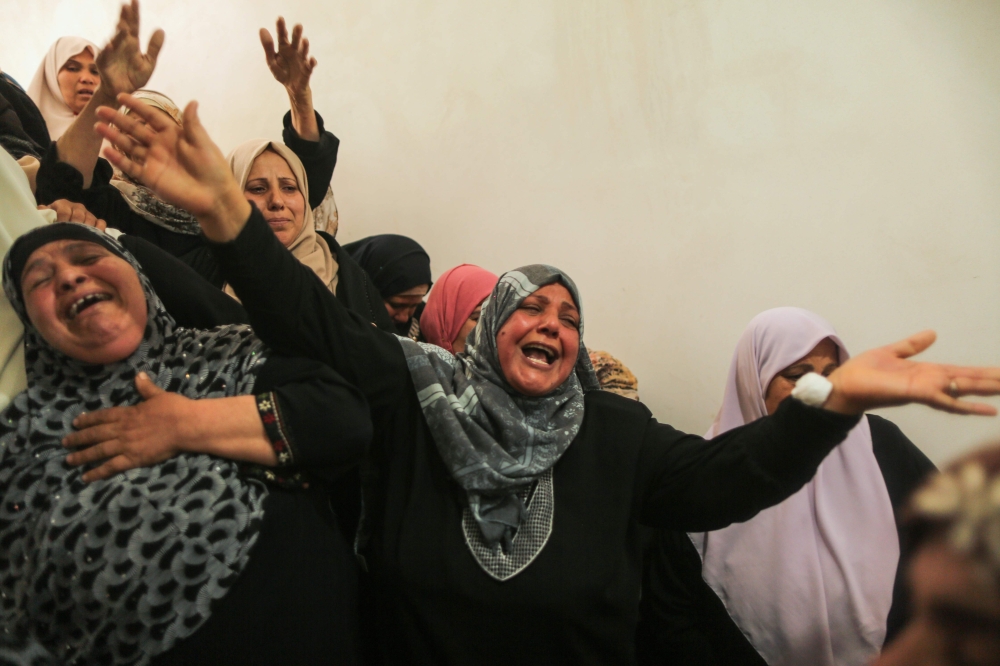Palestinian relatives of Hamdan Abu Amsha, who was killed a day earlier by Israeli forces when clashes erupted as tens of thousands as Gazans marched near the Israeli border with the enclave to mark Land Day, cry during his funeral in Beit Hanun in the northern of Gaza Strip on Saturday. — AFP