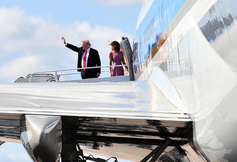 US President Donald Trump waves beside first lady Melania Trump as they board Air Force One upon departure from West Palm Beach, Florida, on Sunday. — AFP