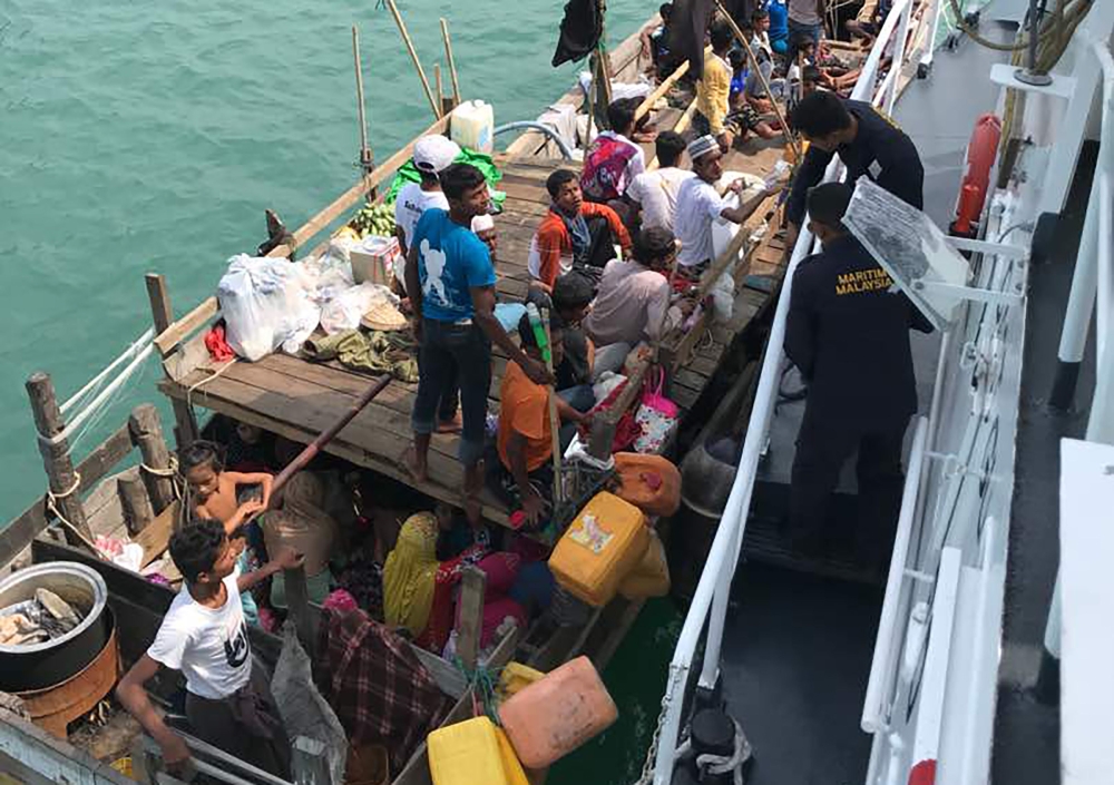 This undated handout photo released by the Malaysian Maritime Enforcement Agency on Tuesday shows members of the Malaysian Maritime Enforcement Agency detaining a boat carrying Rohingya refugees in Malaysian territorial waters off the island of Langkawi. — AFP
