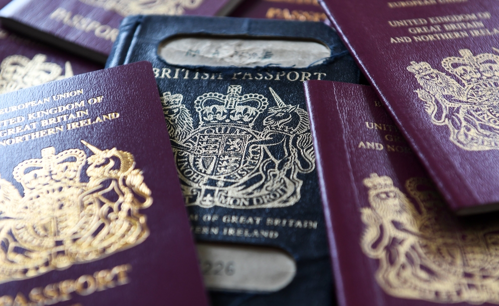 A former blue British passport, center, and the current red EU British passport, left and right, which will be returning to blue when Britain leaves the European Union following an announcement by British Immigration Minister Brandon Lewis on Dec. 22, 2017. — EPA