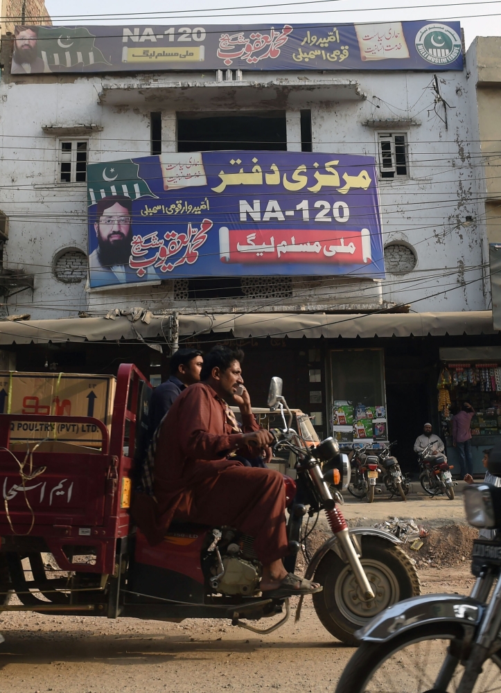Pakistani commuters drive past an abandoned office of the Milli Muslim League (MML) that was launched in August 2017 by Hafiz Saeed’s Jamaat-ud-Dawa (JuD) — the charity wing of militant group Lashkar-e-Tayyiba (LeT) — in Lahore on Tuesday. — AFP
