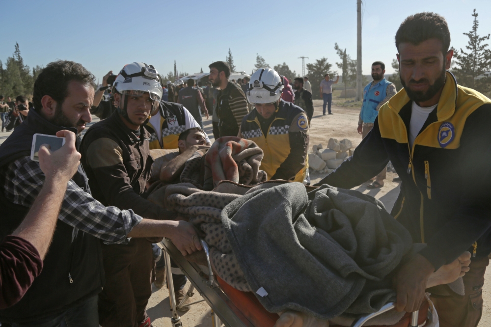 Syrian Civil Defense (known as the White Helmets) carry an injured man as Jaish Al-Islam fighters and their families arrive from the former rebel bastion's main town of Douma at the Abu Al-Zindeen checkpoint controlled by Turkish-backed rebel fighters near the northern Syrian town of Al-Bab. — AFP