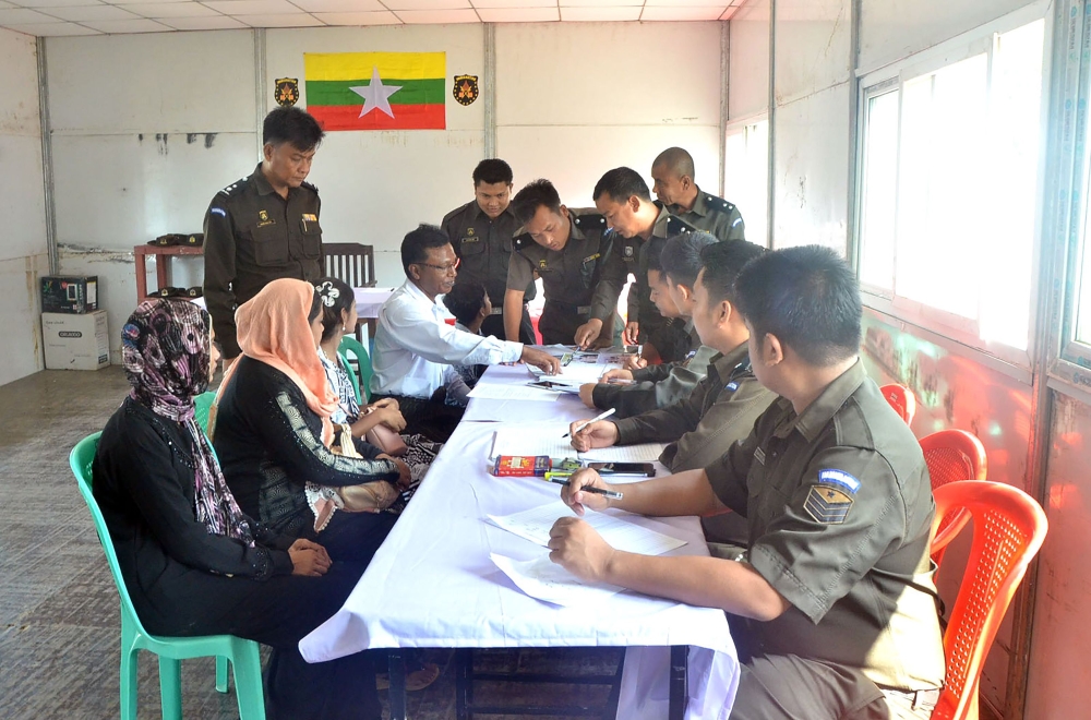 Myanmar immigration official hands over identification document to an unidentified Rohingya woman belonging to the five member Rohingya family at Taungpyoletwei town repatriation camp in Maungdaw near Bangladesh border on Saturday. — AFP