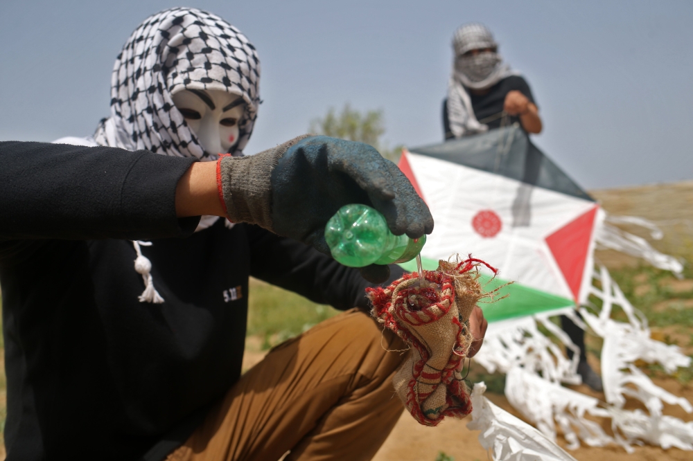 Palestinians prepare a fire bomb to be attached to a kite before trying to fly it over the border fence with Israel, on the eastern outskirts of Gaza City, Friday. — AFP