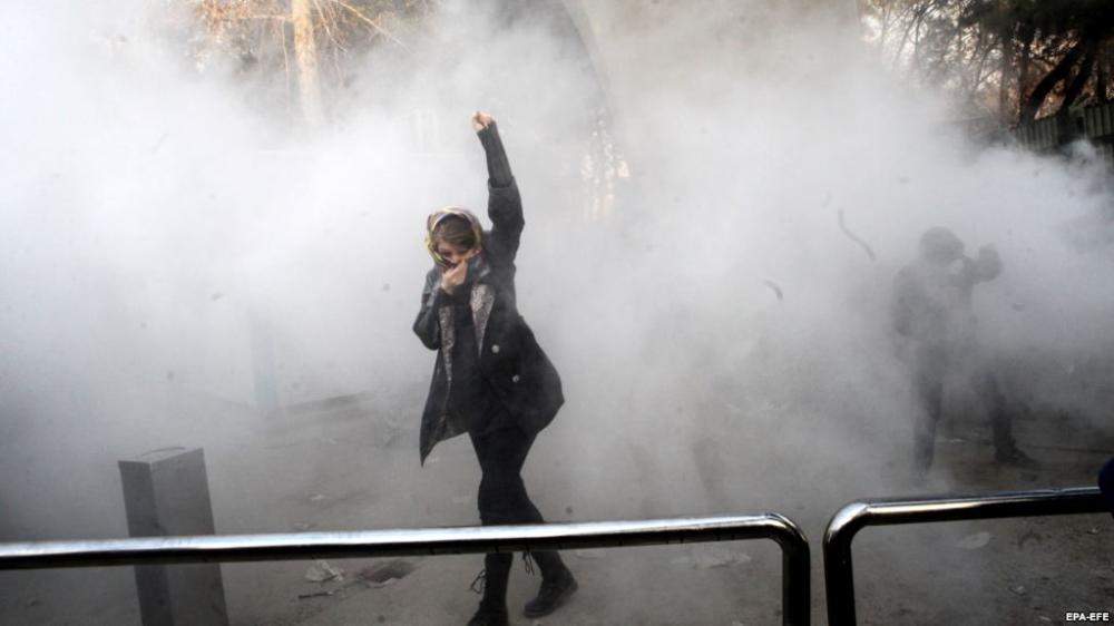 A young woman raises her fist aloft as Iranian students clash with riot police in Tehran. — File photo