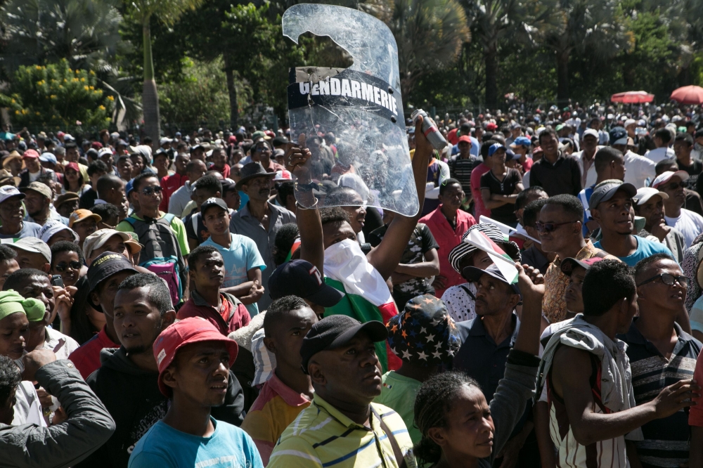 A man holds up a riot police officer's shield as protesters gather in front of city hall during a opposition demonstration against a draft electoral law adopted by Madagascar’s National Assembly in Antananarivo on Saturday. — AFP