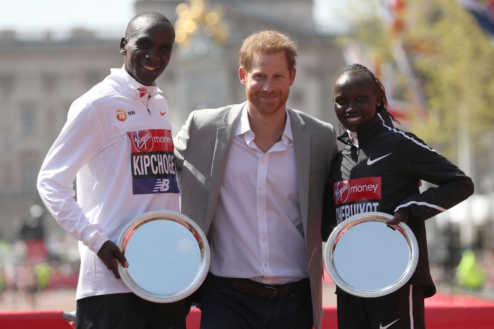 Britain’s Prince Harry (C) poses with elite men’s race winner Kenya’s Eliud Kipchoge (L) and elite women’s race winner Kenya’s Vivian Cheruiyot during the trophy ceremony of the 2018 London Marathon in central London Sunday. — AFP