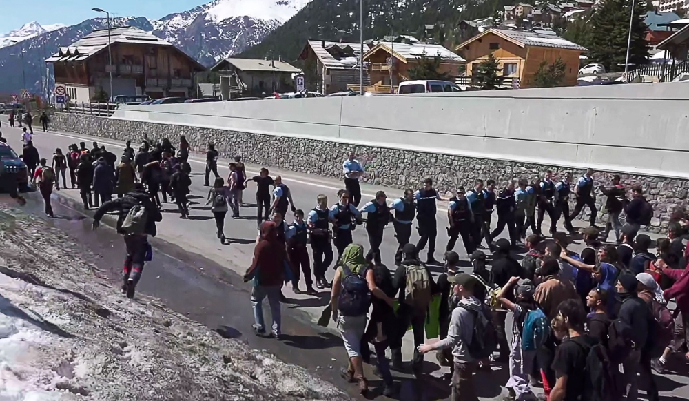 This video grab taken from a footage released and filmed by Italian news video platform Local Team onSunday, at Montgenevre on the border between France and Italy in the Alps, in the Alps, shows French gendarmes standing guard as demonstrators take part in a protest walk to help nearly 30 migrants to cross the border to France. — AFP