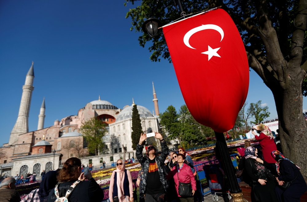 People, with the Byzantine-era monument of Hagia Sophia in the background, take pictures at Sultanahmet square in Istanbul, Turkey. — Reuters