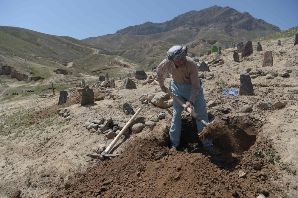 An Afghan man digs a grave for one of the 57 victims of a bomb blast before the burial a day after the attack on a voter registration center in Kabul on Monday. — AFP