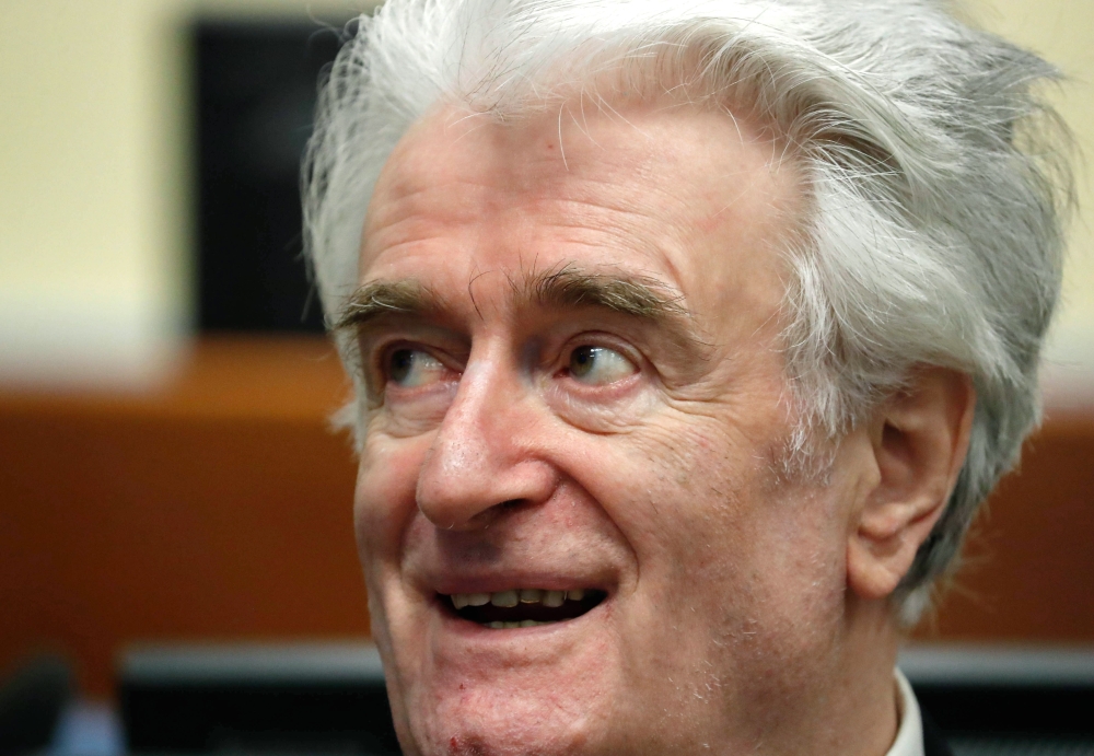 Former Bosnian Serb leader Radovan Karadzic smiles as he appears in a courtroom before the International Residual Mechanism for Criminal Tribunals (MICT), in The Hague, on Tuesday on the second day of his appeal hearing after he was jailed for 40 years for war crimes and genocide. — AFP