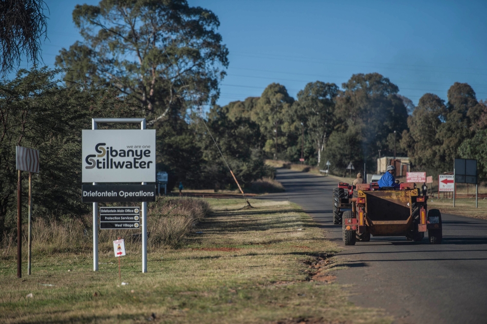 Workers drive past a sign of the Sibanye-Stillwater Driefontein gold mine near Carletonville, near Johannesburg, on Saturday. — AFP