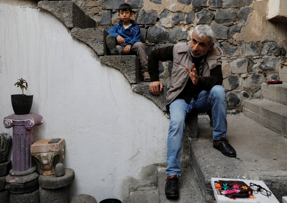 Sukru Gunduz, a Sur resident whose house was demolished, and his son sit on the stairs of their rented home in Sur, a historical district of the southeastern city of Diyarbakir, Turkey. — Reuters