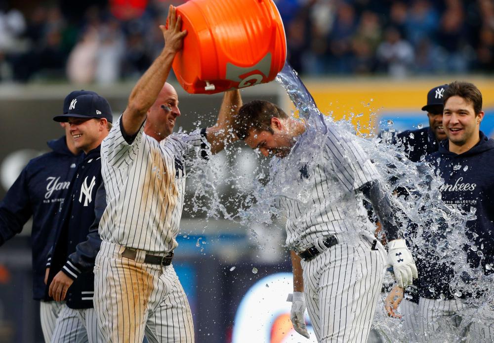 Brett Gardner of the New York Yankees douses teammate Neil Walker after his eleventh inning game-winning base hit against the Oakland Athletics at Yankee Stadium in the Bronx borough of New York City Saturday. — AFP 
