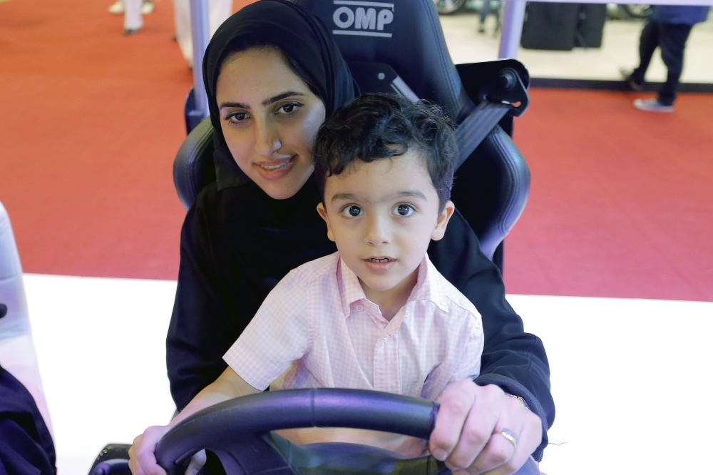 A women with a child sits in a driving simulator during a car show only for women in Riyadh. — EPA