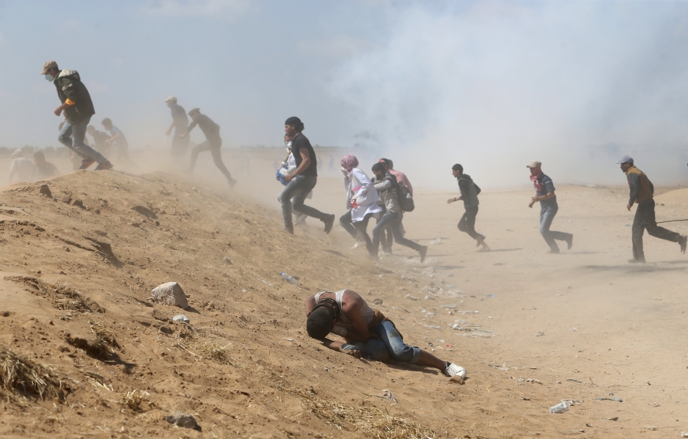 A Palestinian reacts as others run from tear gas fired by Israeli forces during a protest marking the 70th anniversary of Nakba (catastrophe) at the Israel-Gaza border in the southern Gaza Strip on Tuesday. — Reuters