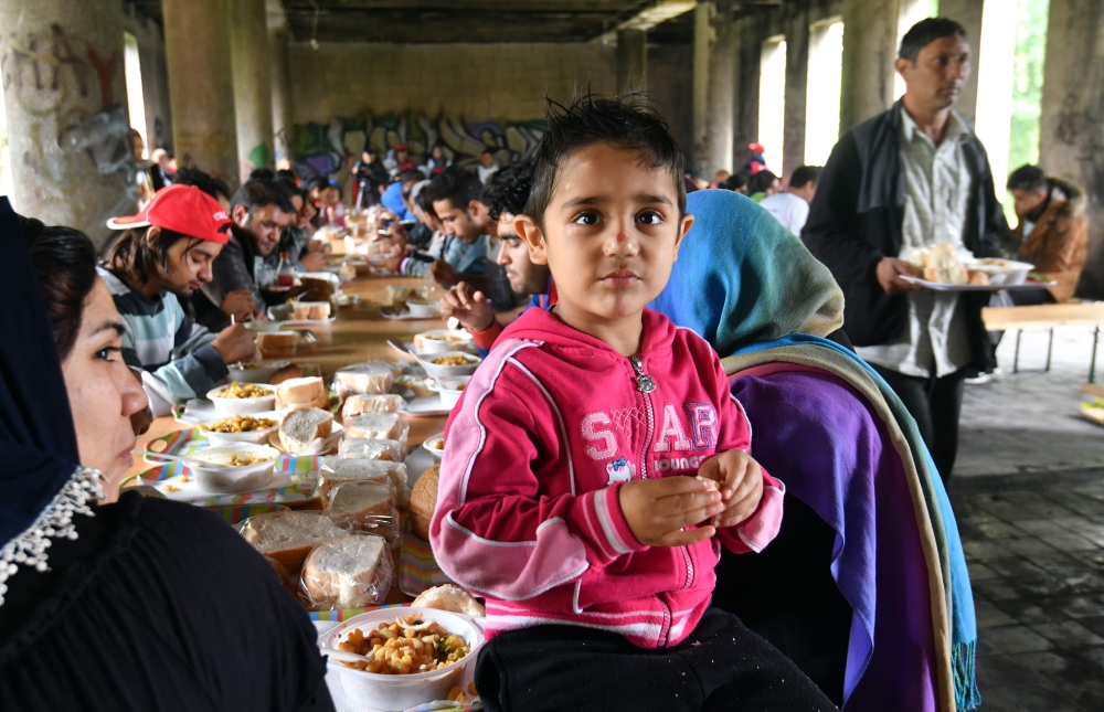 Migrants and their children are having lunch in an abandoned building in the north-western Bosnian town of Bihac. The building is being refitted with infrastructure to accept African-Asian migrants who make their stop in Bihac, where they rest before continuing 
