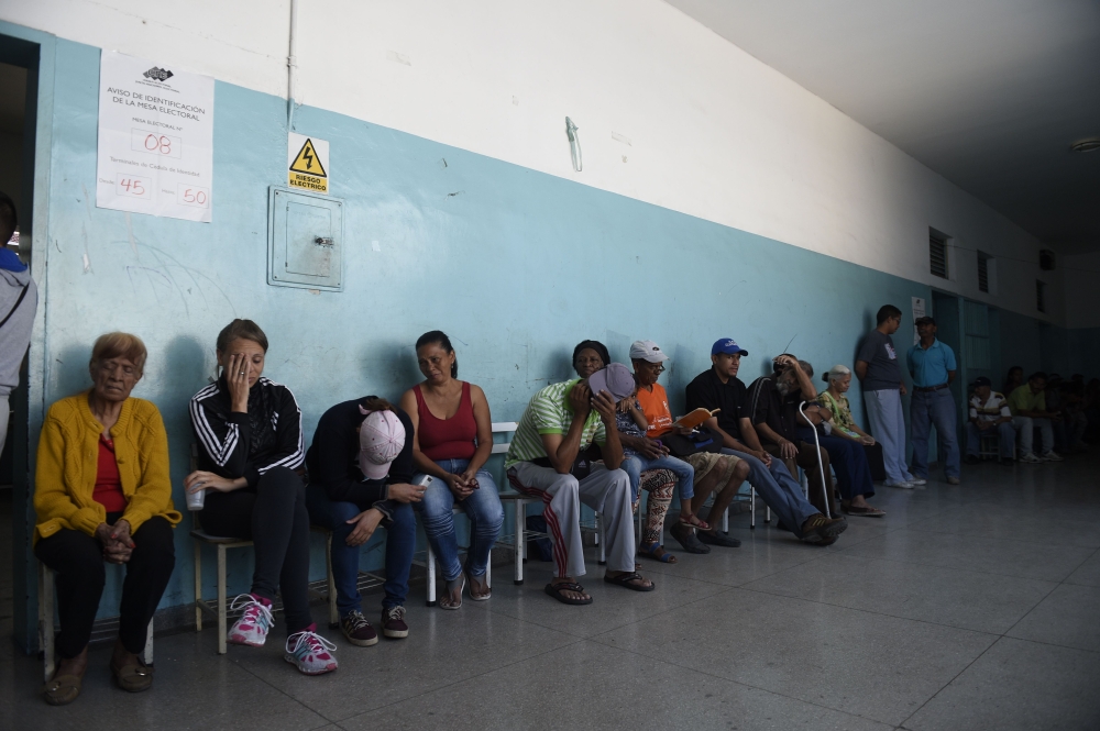 Venezuelans queue inside a polling station as they wait to cast their vote during the presidential elections in Caracas on Sunday. — AFP