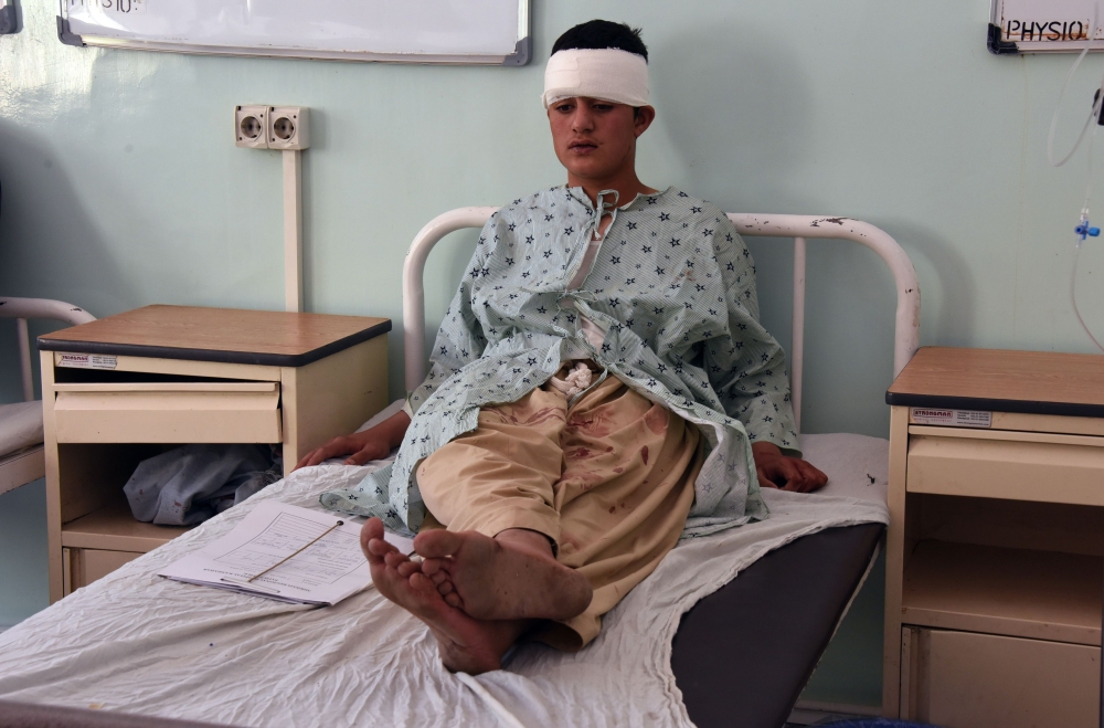 A wounded Afghan man sits on a bed at a hospital after a minivan stuffed with explosives detonated in Kandahar on Tuesday. — AFP