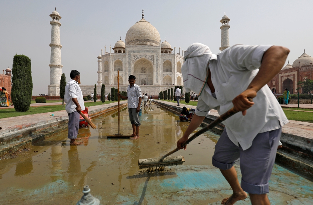 Laborers clean the fountain in the historic Taj Mahal premises in Agra, India, on Saturday. — Reuters