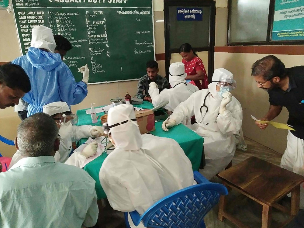 Medical personnel wearing protective suits check patients at the Medical College hospital in Kozhikode, Kerala, on Monday. — AFP