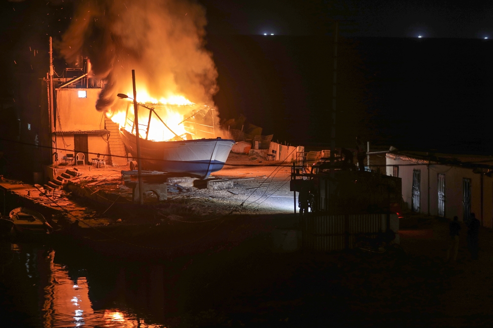 Palestinian firefighters inspect a burning fishing boat after an Israeli airstrike in in west Gaza City early Wednesday. — EPA
