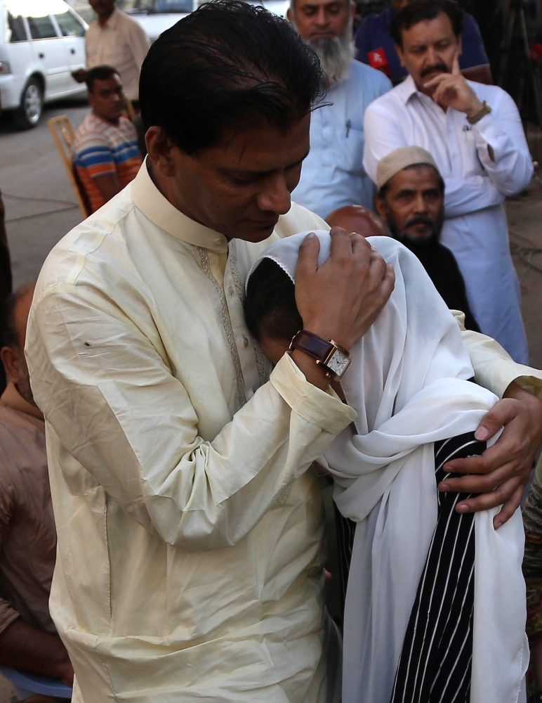 Abdul Aziz Sheikh, father of Sabika Sheikh, an exchange student from Pakistan who was killed in shooting at school in Texas, US, comforts relatives during her funeral in Karachi, Wednesday. — EPA