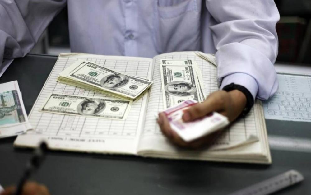 A man counts US dollars and Myanmar kyats at a money changer in Yangon in this file photo.  — Reuters