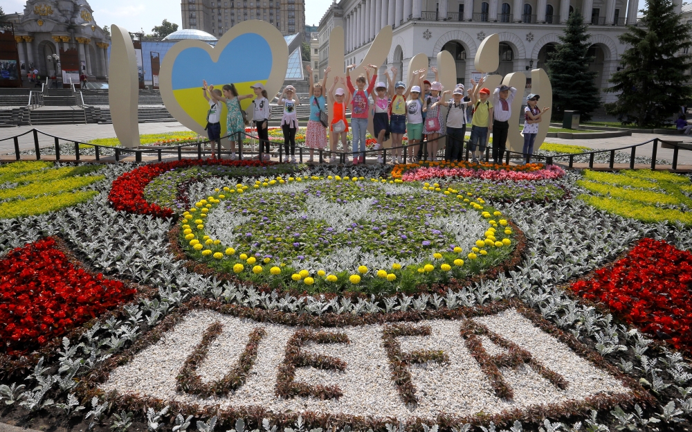 A group of children poses for a snapshot in front of floral arrangements in Maidan Square, Kiev, Ukraine, on Friday. In the picture, the UEFA Champions League final logo was crafted among the flowers (front).  — EPA