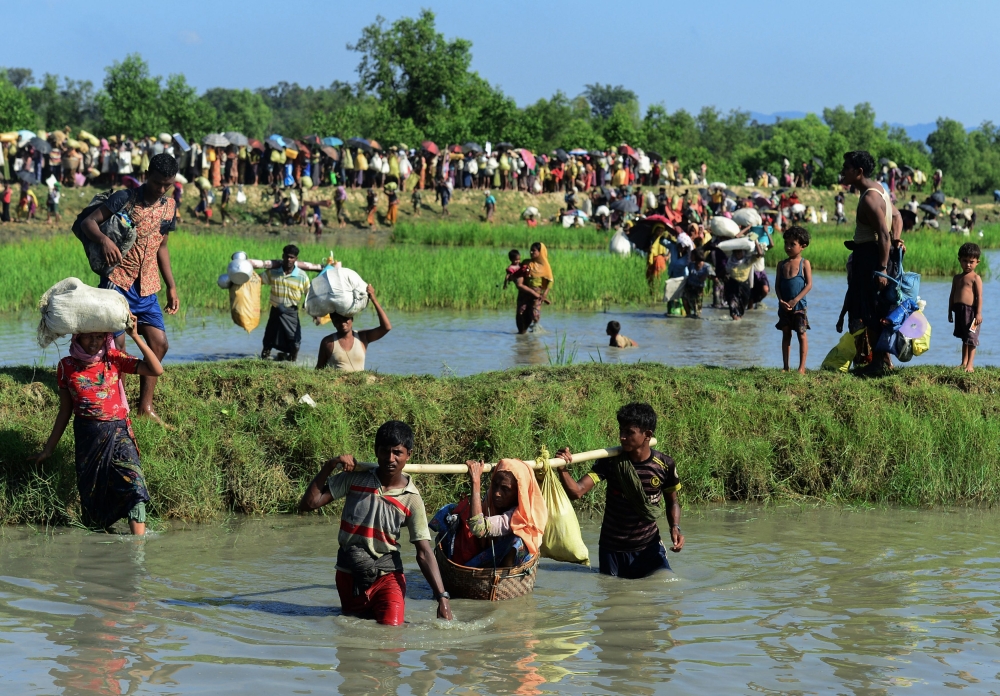 Rohingya refugees carry a woman over a canal after crossing the Naf River as they flee violence in Myanmar to reach Bangladesh in Palongkhali near Ukhia. It takes a few moments to sift through the years of chaos and dislocation before Rohingya refugee Robi Alam settles on Eid Al-Fitr, August 2012, as the last time he saw his seven brothers together in Myanmar. 